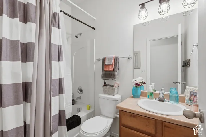 Main floor full bathroom.  Bathroom featuring a vanity with a neutral-toned countertop and an integrated oval sink, a shower-tub combination with a white surround, and an industrial-style three-light fixture