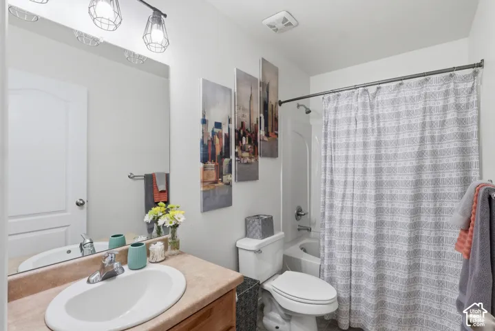 Bathroom featuring a vanity with a countertop, an integrated sink, a full-width mirror, industrial-style multi-light fixture, and a tub-shower combination