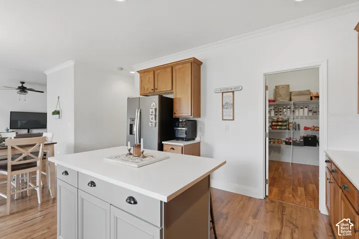 Kitchen featuring a central island with a solid surface countertop, wood cabinetry, built-in pantry with wire shelving, and wood-finish flooring