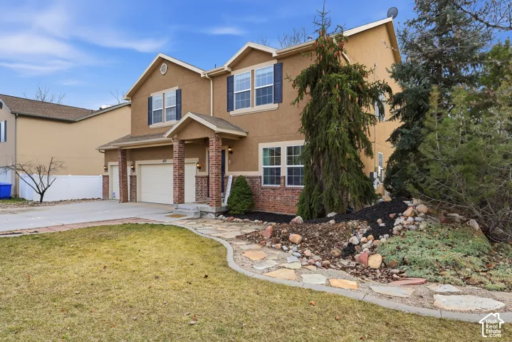 Two-story residence featuring a stucco and brick exterior, multi-gabled roofline, flagstone walkway, and attached two-car garage