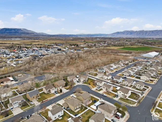 Aerial perspective of a residential neighborhood featuring mountain topography, expansive open space, paved street infrastructure, and varied suburban home designs