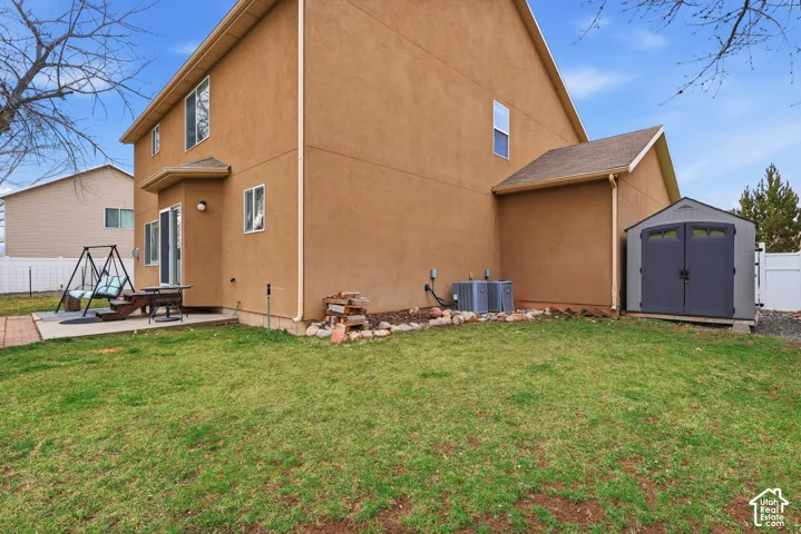 Exterior facade featuring stucco siding, a concrete patio, and a detached storage shed situated on a fenced lot