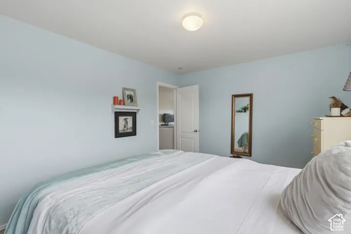 Bedroom interior featuring light-toned wall paint, a flush-mount ceiling light fixture, and a solid-core interior door with a brushed-metal lever handle