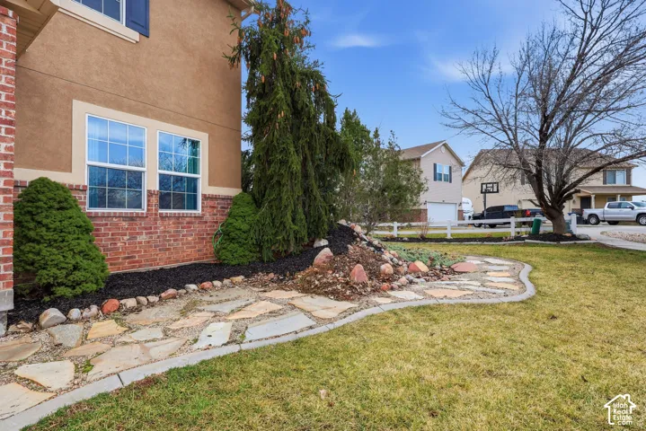 Stucco and brick facade with flagstone landscaping, decorative rock accents, and manicured shrubbery