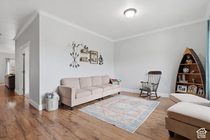 Living area featuring wood-finish flooring, neutral wall paint, and crown molding