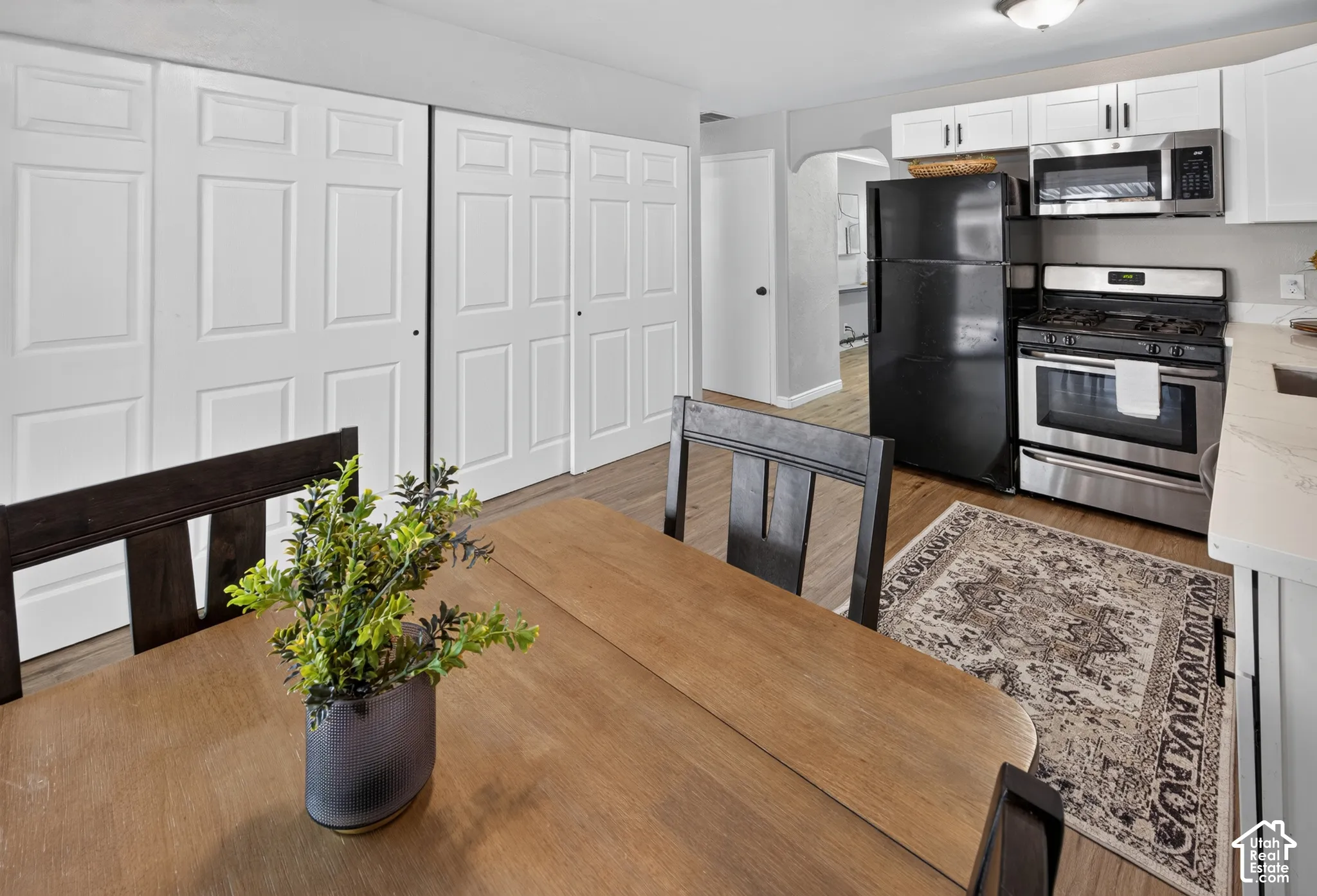 Kitchen featuring white cabinetry, wood-finish flooring, stainless steel gas range, built-in microwave, and floor-to-ceiling multi-panel interior doors