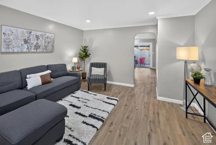 Wood-finish flooring, recessed lighting, crown molding, and an arched doorway