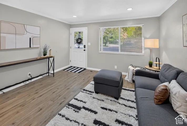 Neutral-toned interior space featuring wood-finish flooring, recessed lighting, a multi-pane window, and an entry door with a glass inlay