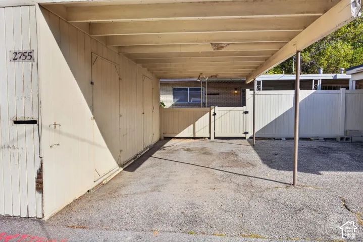 Covered carport featuring integrated storage cabinetry and a white vinyl privacy fence