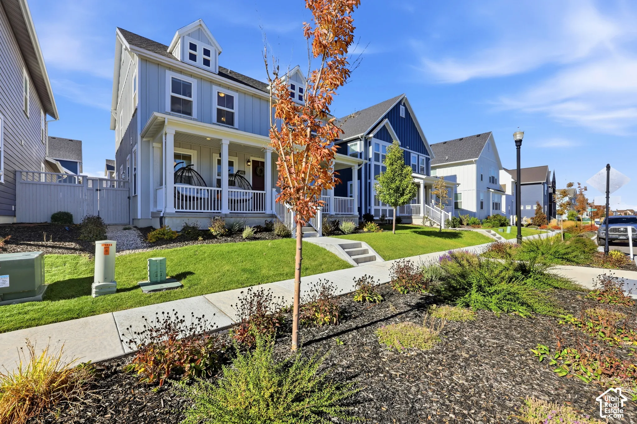 Two-story residence featuring vertical siding, a covered front porch with white railing, and dormer windows