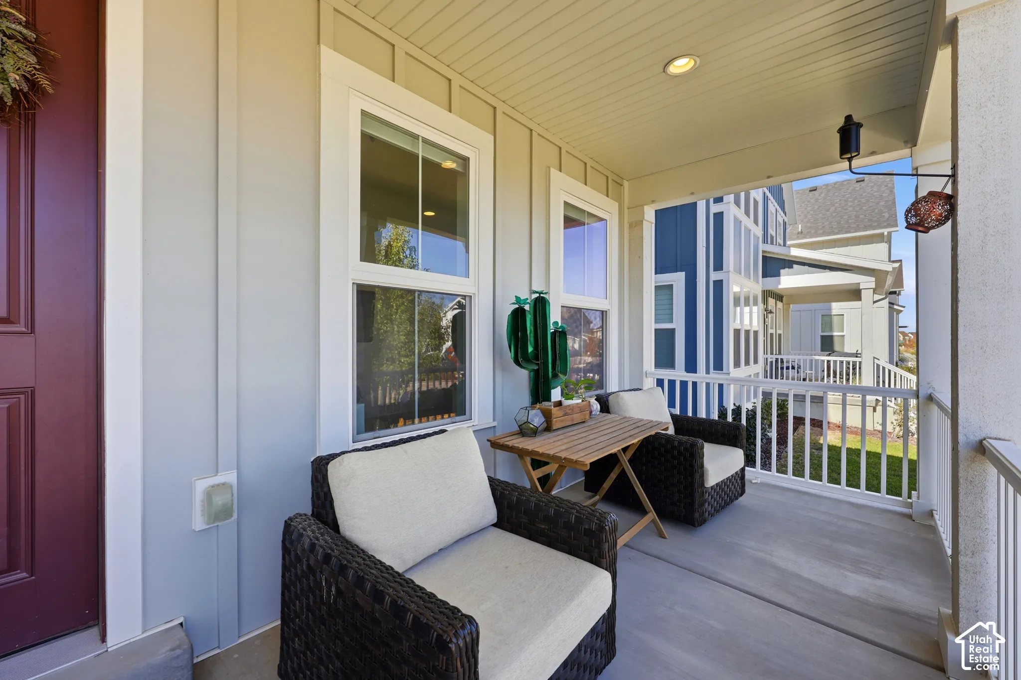Covered front porch featuring board-and-batten siding, recessed lighting, and white balustrade railings