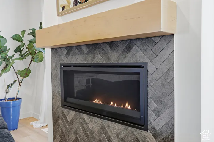 Fireplace featuring dark-toned stone tile in a herringbone pattern, a natural wood-finish mantel, and a sleek black metallic surround