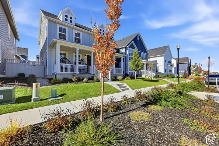 Two-story residence featuring vertical siding, a covered front porch with white railing, and dormer windows