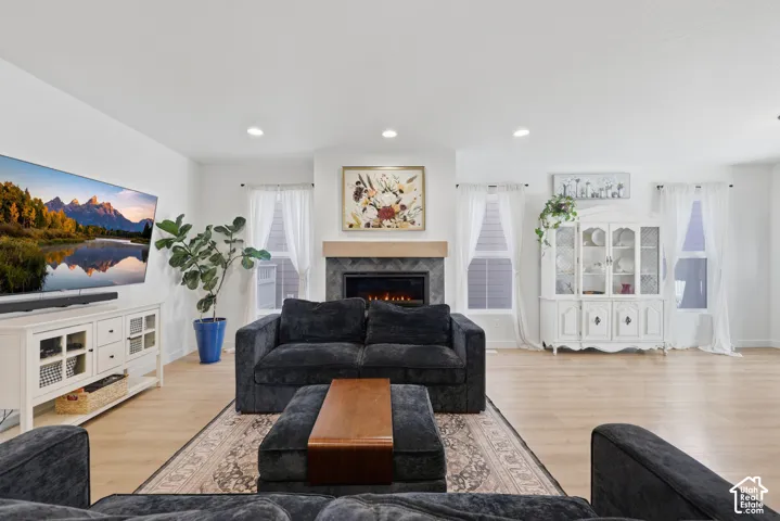 Living area featuring wood-finish flooring, recessed lighting, and a fireplace with a stone-tile surround and wooden mantel
