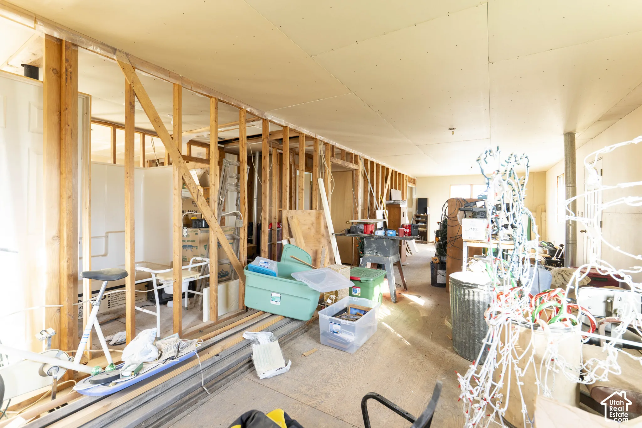Open interior space featuring exposed wood-stud wall framing, finished ceiling panels, and floor-to-ceiling structural elements