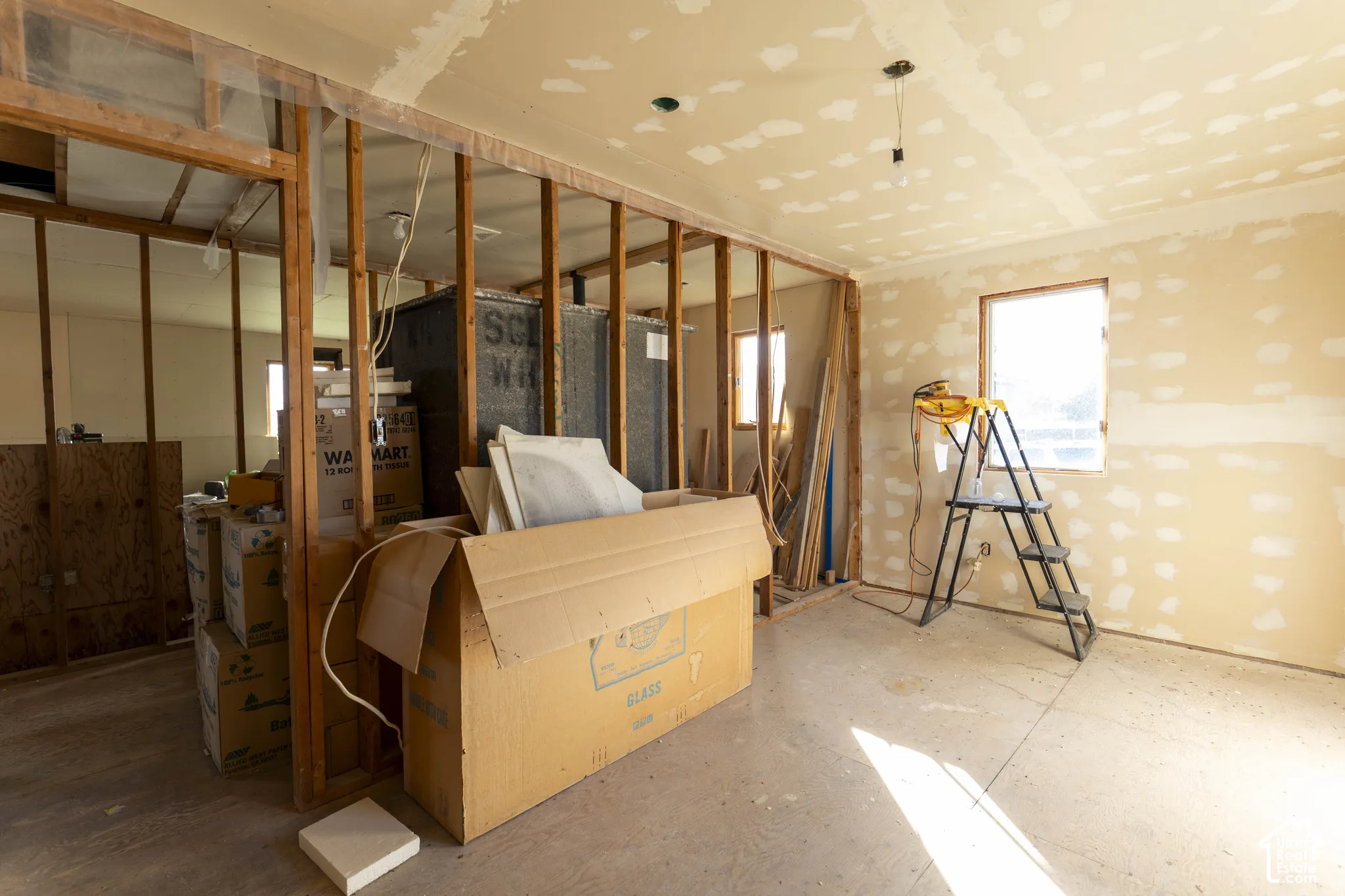 Interior space featuring exposed wood stud wall framing, partially finished drywall, and a single-pane window