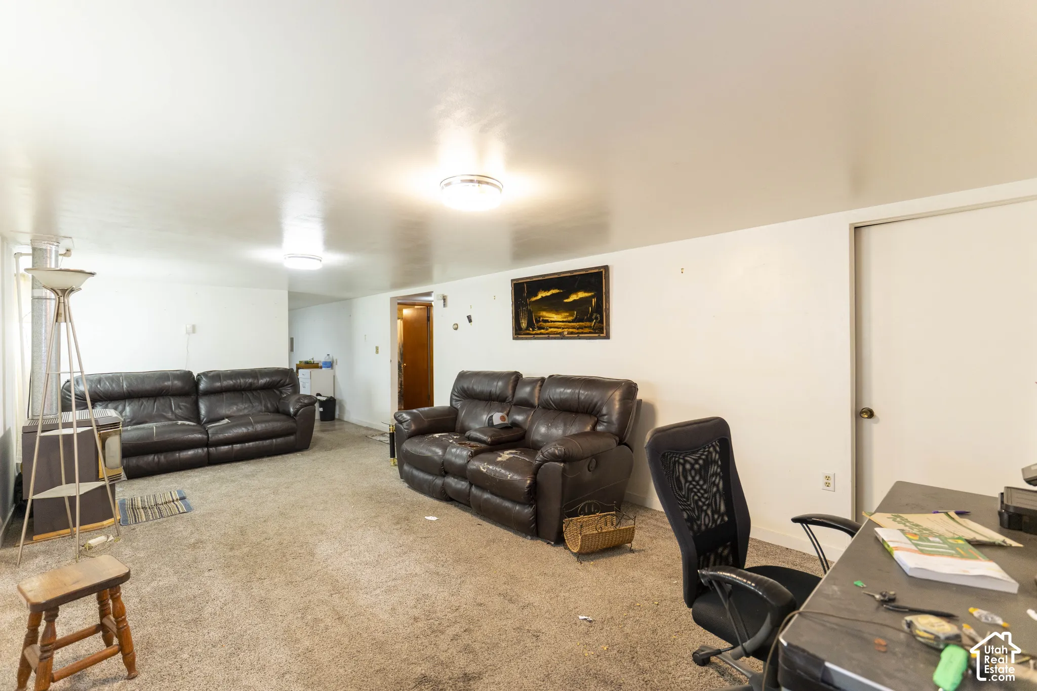 Neutral-toned interior space featuring carpeted flooring, flush-mount ceiling lighting, and a metal wood-burning stove