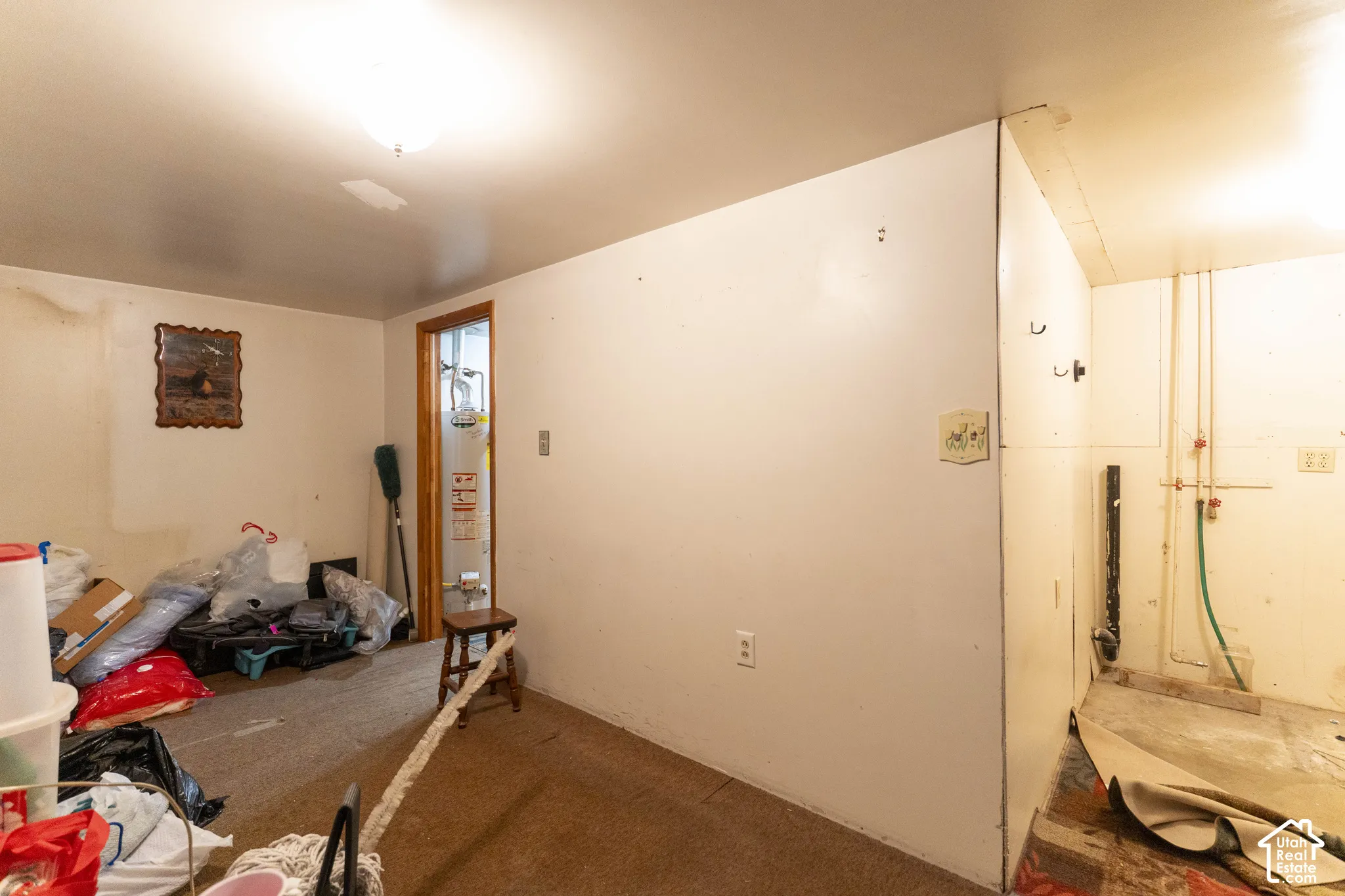 Interior space featuring exposed plumbing connections, an attached water heater, and wall-mounted lighting