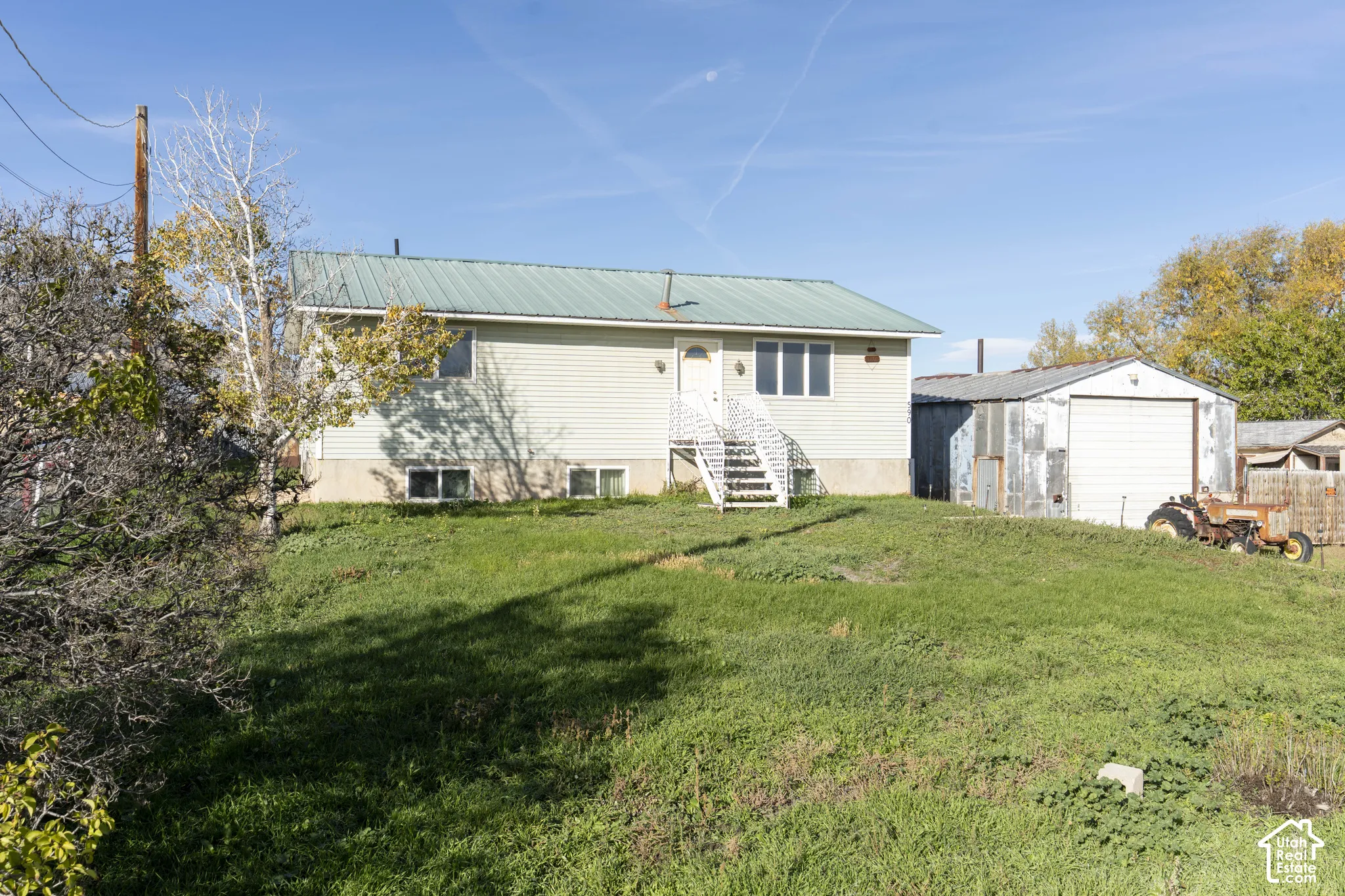 Single-story residence featuring light-colored siding, a metal roof, and an attached garage with a roll-up door