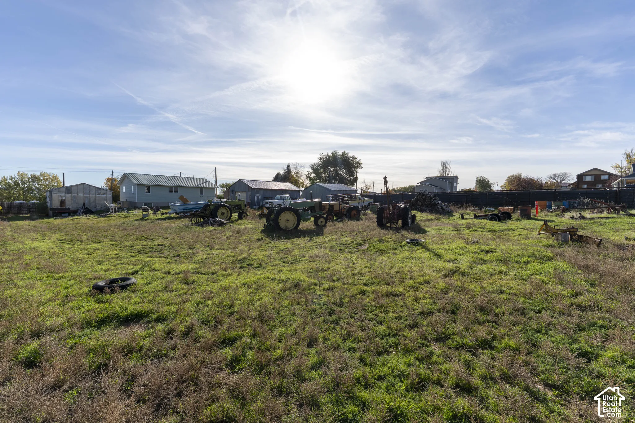 Expansive acreage featuring open green space, multiple detached metal structures, and a perimeter fence