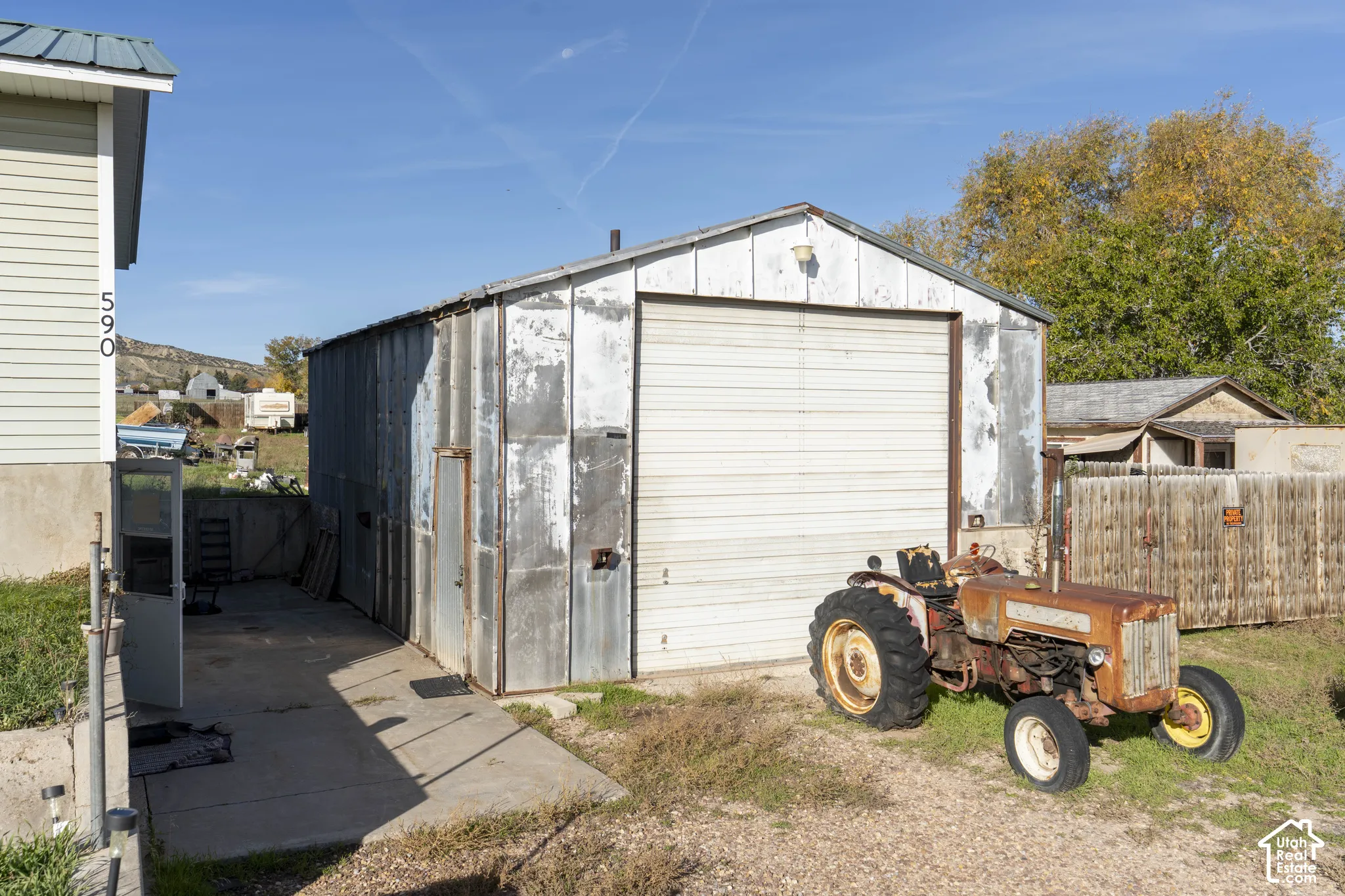 Detached metal-sided structure featuring a metal roll-up door, side-entry door, and concrete paved approach
