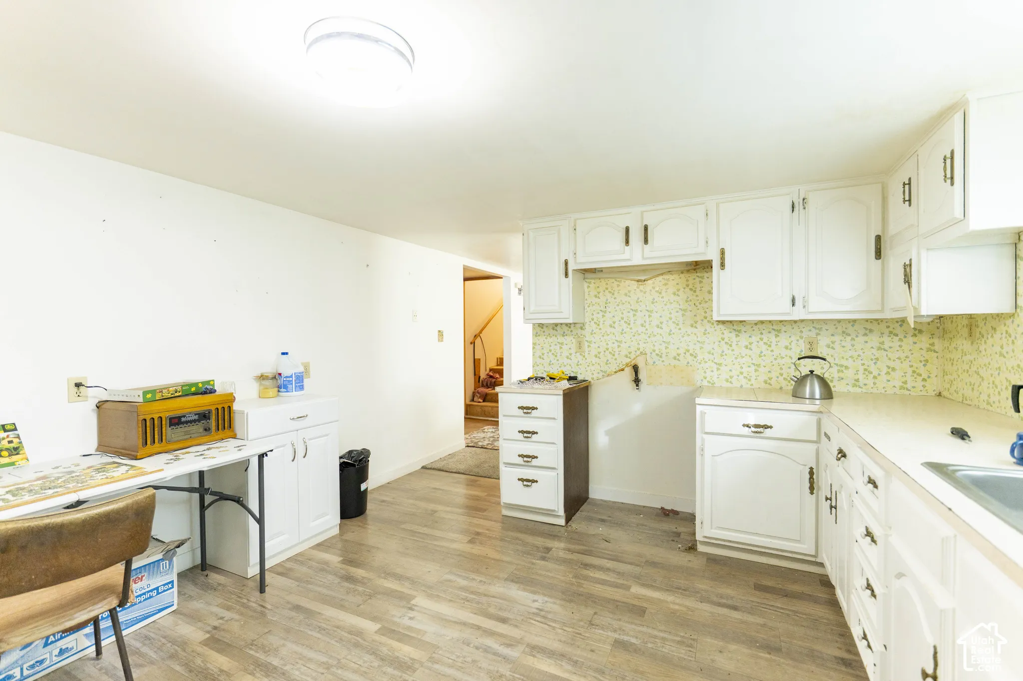 Kitchen featuring white cabinetry, light-toned countertops, wood-finish flooring, and a flush-mount ceiling light fixture