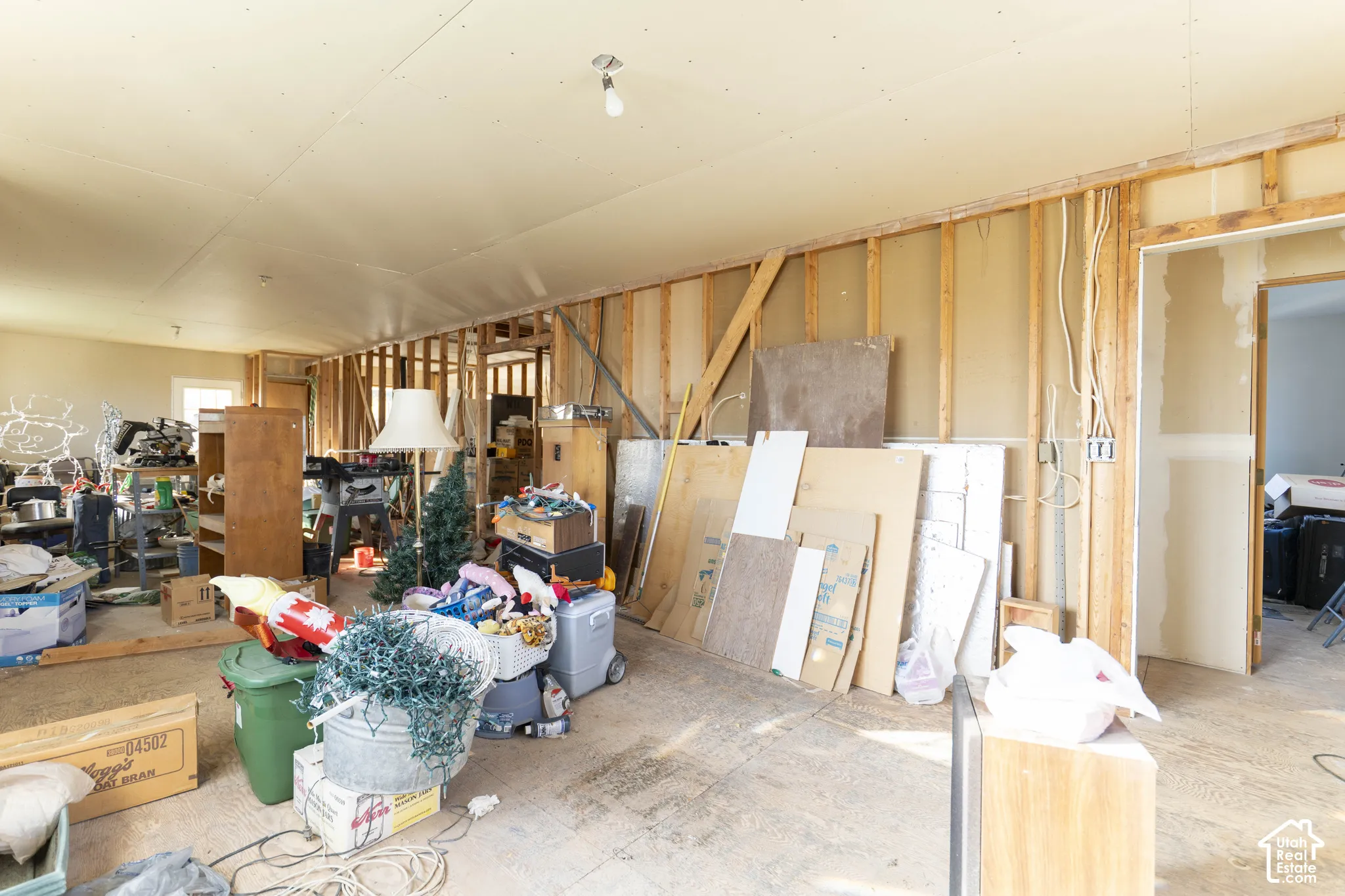 Open-concept interior space featuring unfinished wall framing, exposed stud work, and partially installed drywall ceiling