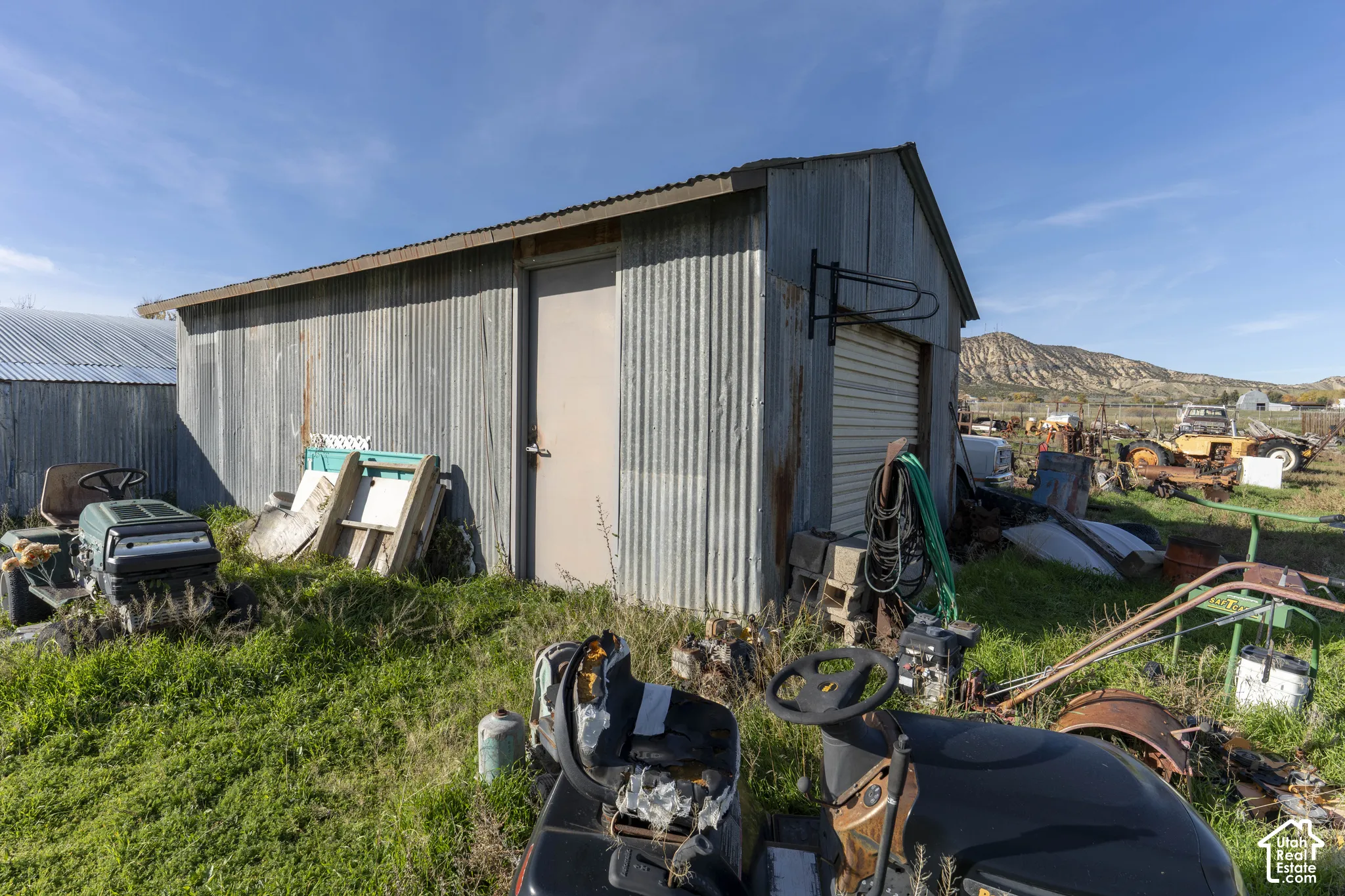Outbuilding featuring a corrugated metal exterior, metal roofing, a roll-up door, and a dedicated entry door