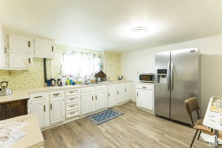 Kitchen featuring white cabinetry, wood-finish flooring, and a stainless steel side-by-side refrigerator