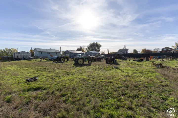 Expansive acreage featuring open green space, multiple detached metal structures, and a perimeter fence