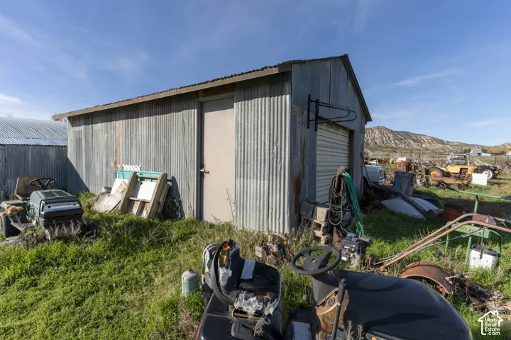 Outbuilding featuring a corrugated metal exterior, metal roofing, a roll-up door, and a dedicated entry door