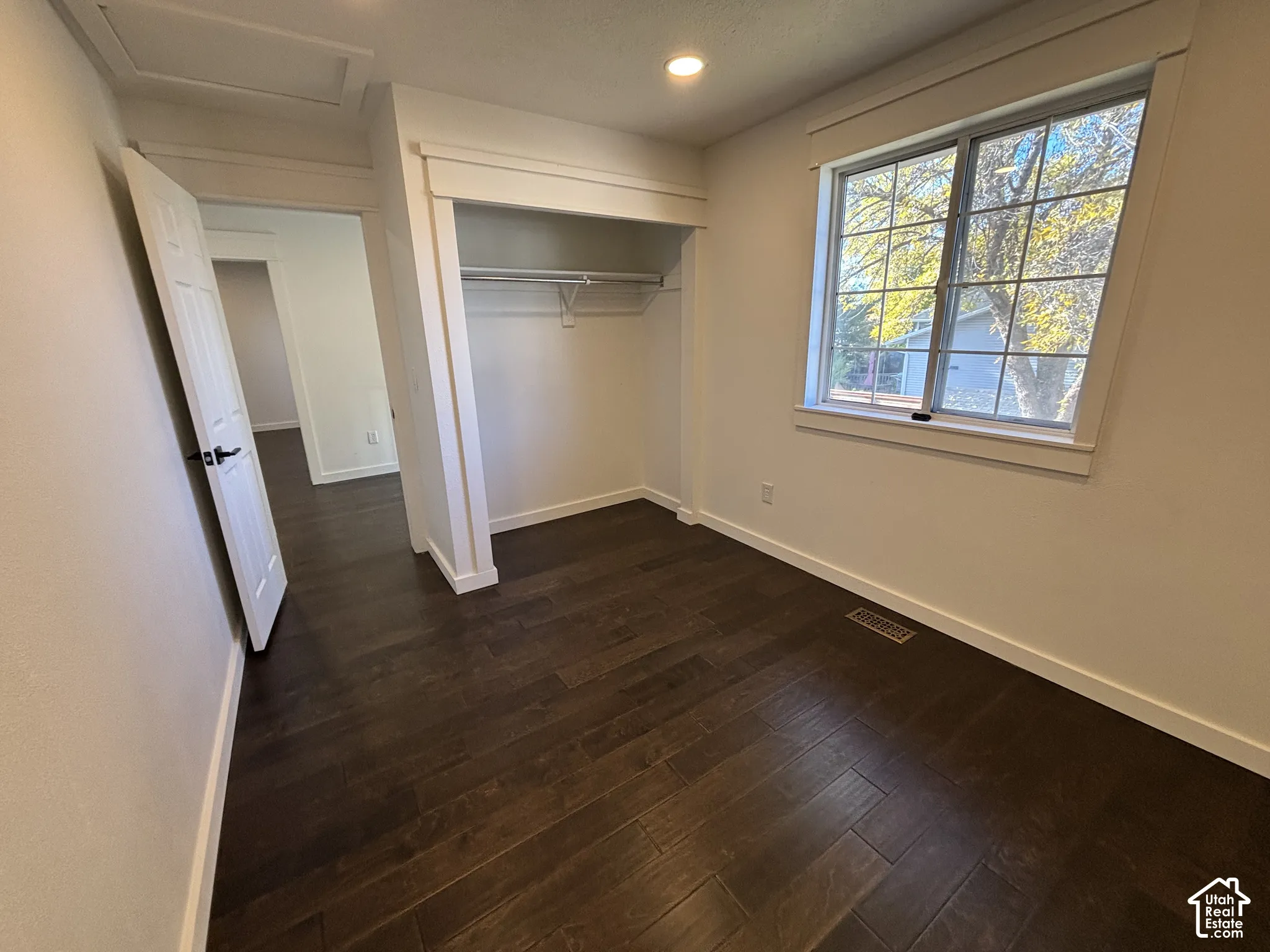 Room featuring wood-finish flooring, recessed lighting, a multi-pane window with custom trim, and a built-in closet with shelving