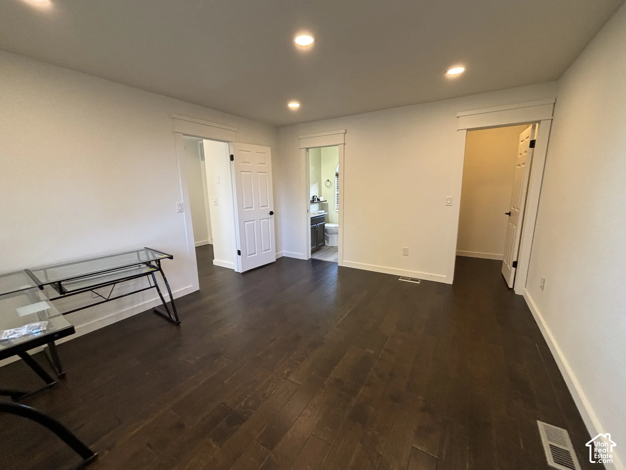 Dark wood-finish flooring, recessed lighting, and crisp white trim detailing