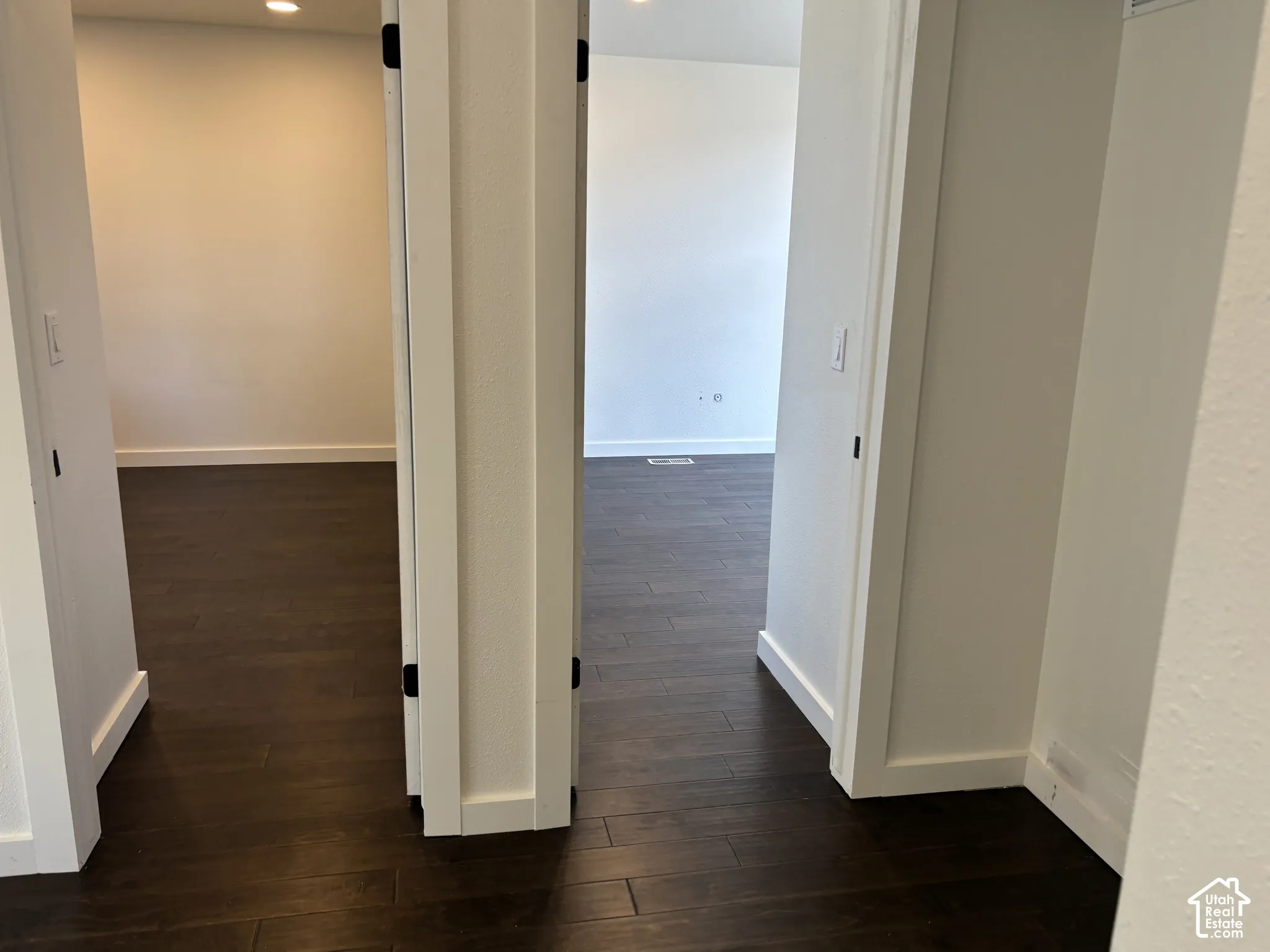 Dark wood-finish flooring, crisp white interior walls, and recessed lighting