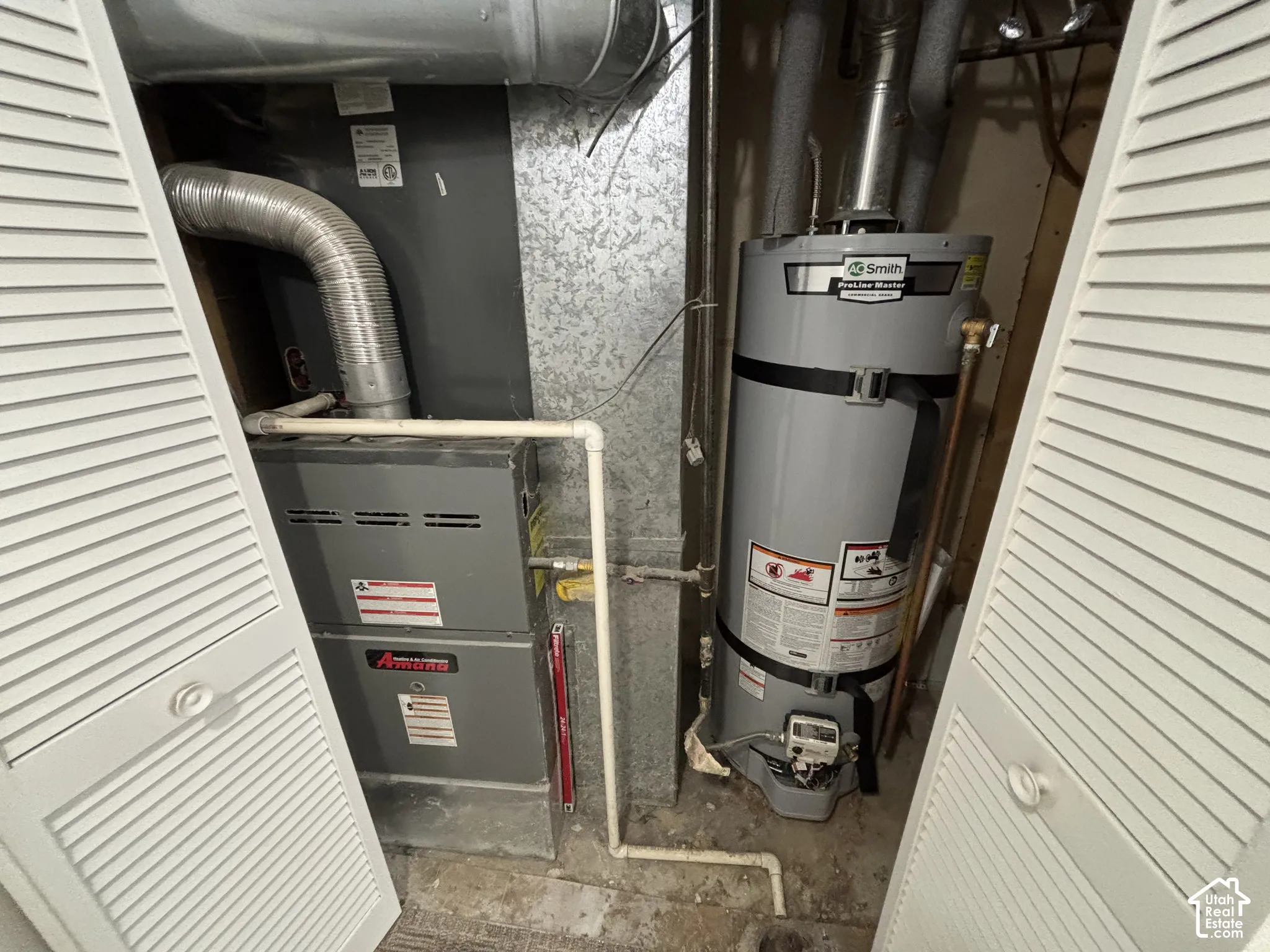 Utility closet housing a forced-air furnace and a vertical water heater with rigid metal venting and integrated piping