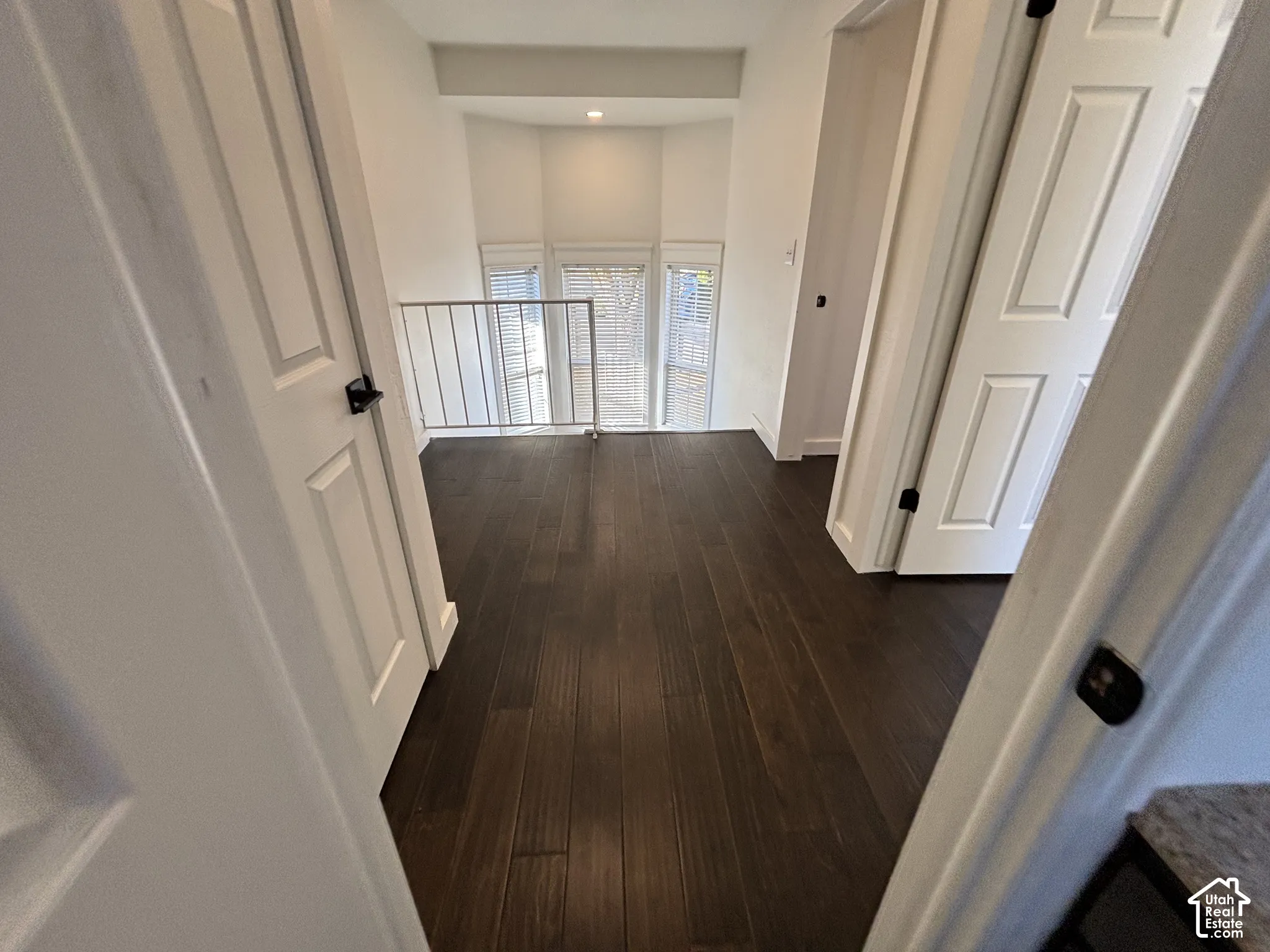 Landing area featuring wood-finish flooring, a metal stair railing, and a bay window configuration