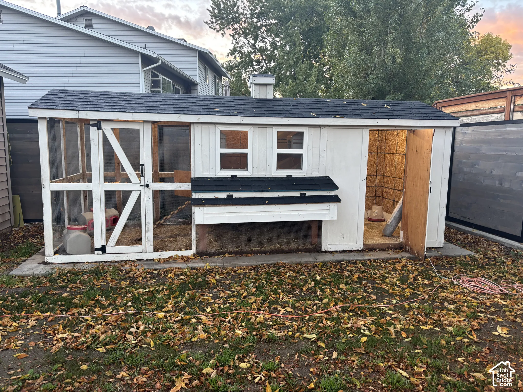 Exterior outbuilding featuring a shingle roof, painted wood siding, screen-enclosed framing, and dual windows