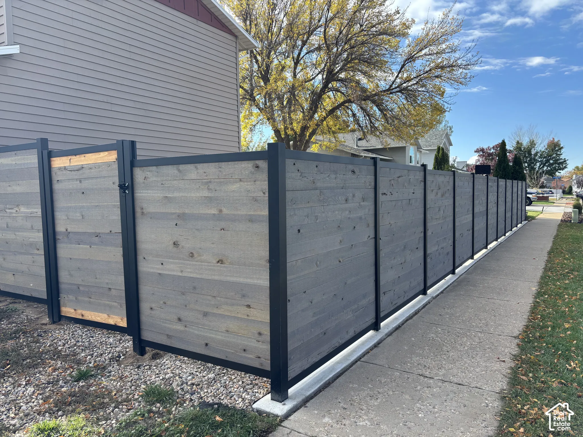 Horizontal wood-plank privacy fencing featuring matte black metal framing and a matching integrated gate