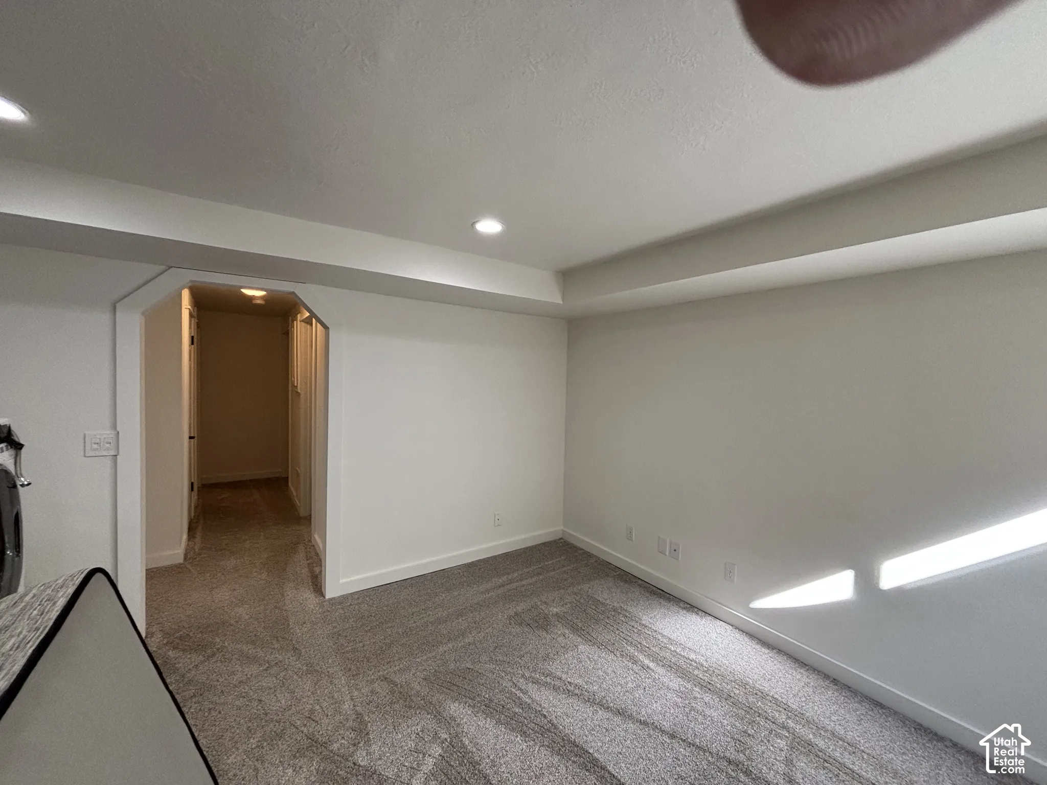 Neutral wall palette with recessed lighting and carpeted flooring, featuring a chamfered doorway entry