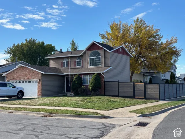 Two-story residence featuring brick and horizontal siding exterior, arched windows, attached two-car garage, and a horizontal privacy fence