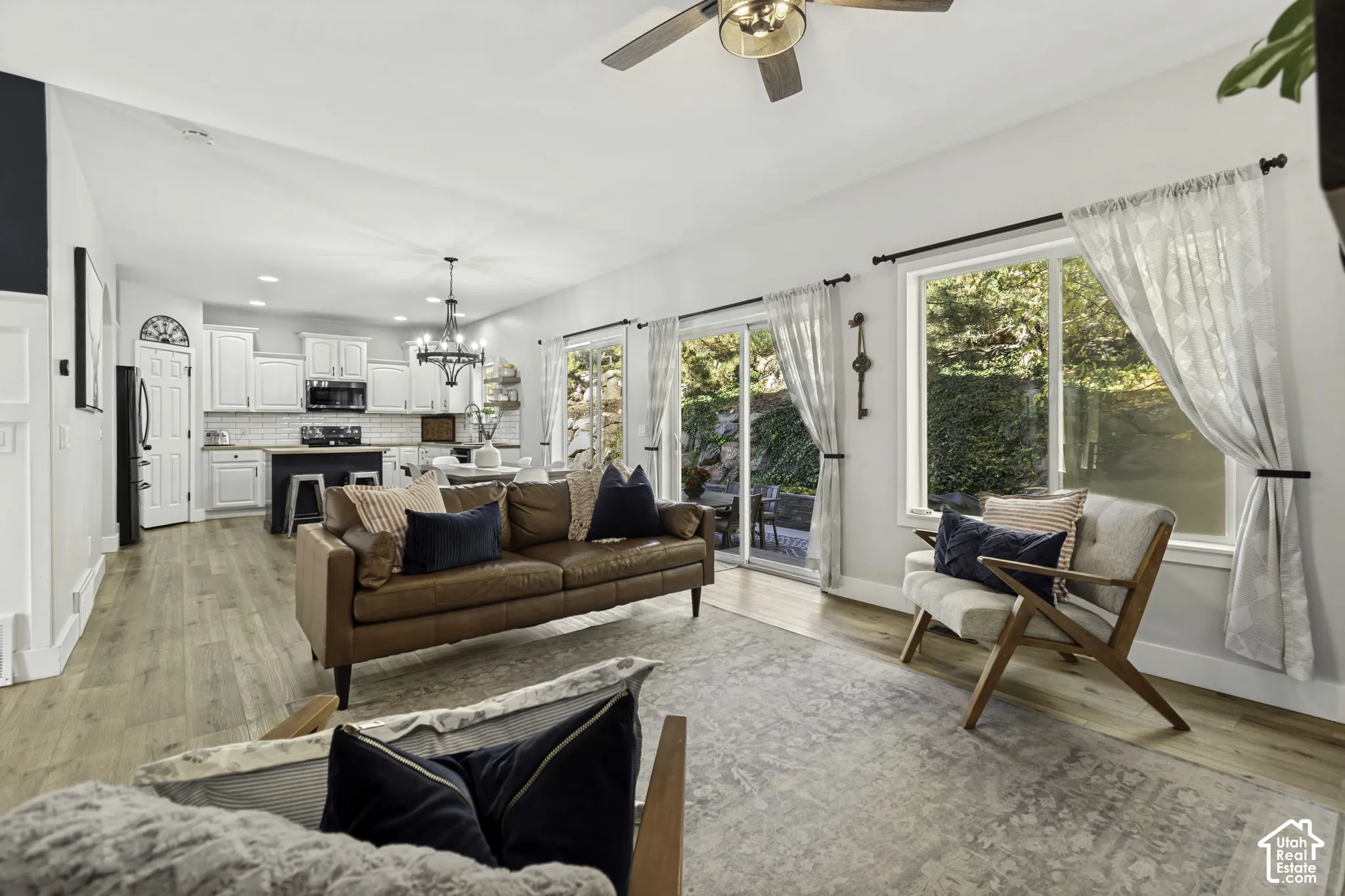 Open-concept floor plan featuring wood-finish flooring, sliding glass doors, white cabinetry, and a tiered chandelier