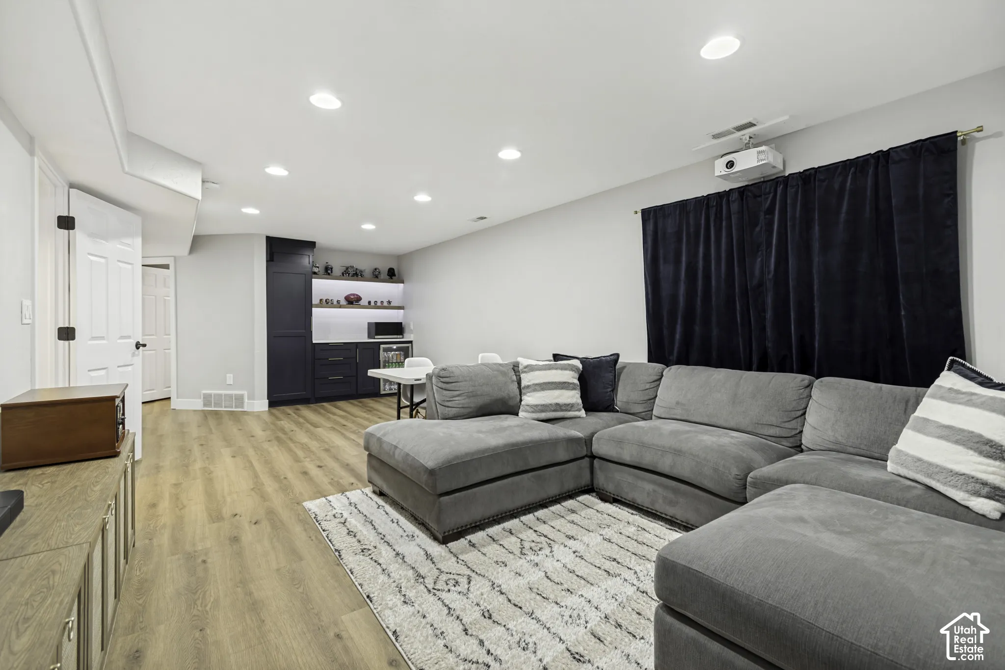 Recessed lighting, wood-finish flooring, and built-in cabinetry featuring integrated shelving, under-cabinet lighting, and a beverage cooler