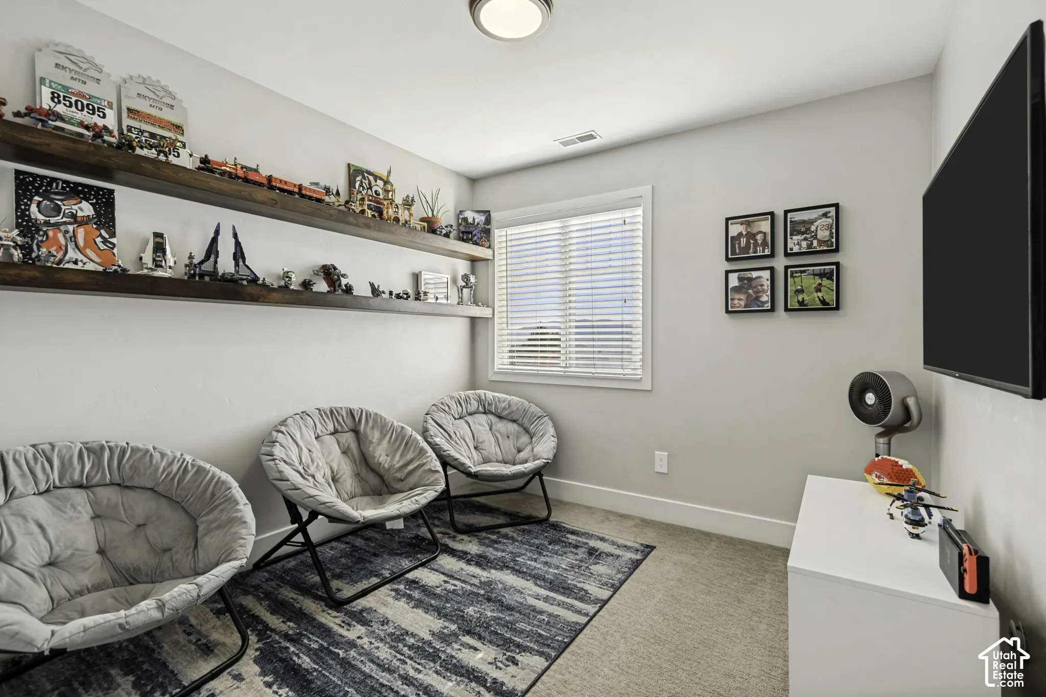 Room featuring dual stained wood floating shelves, a centered window with horizontal blinds, and neutral wall-to-wall carpeting