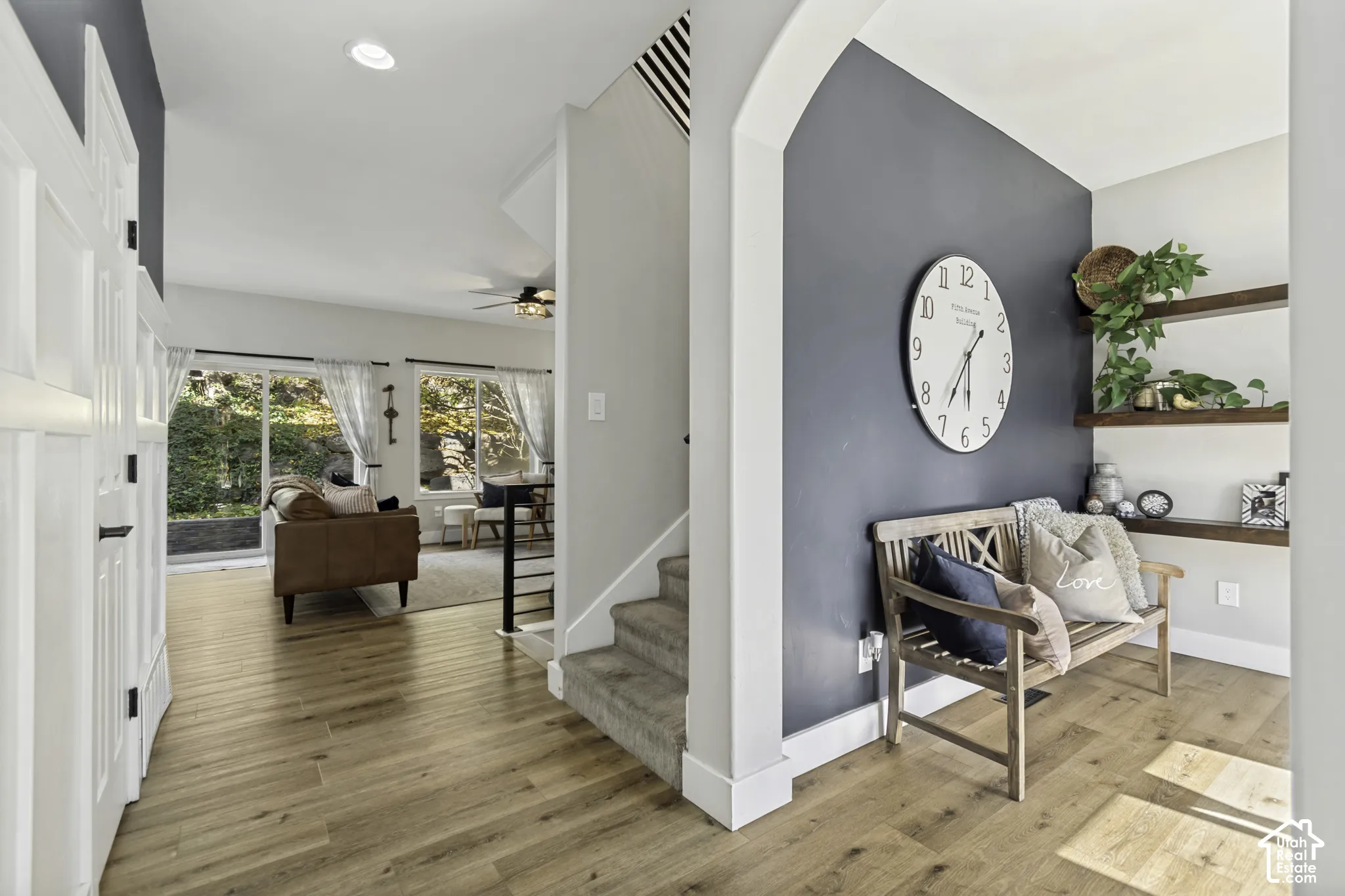 Entryway featuring an arched architectural opening, wood-finish flooring, recessed lighting, and wall-mounted floating wood shelving