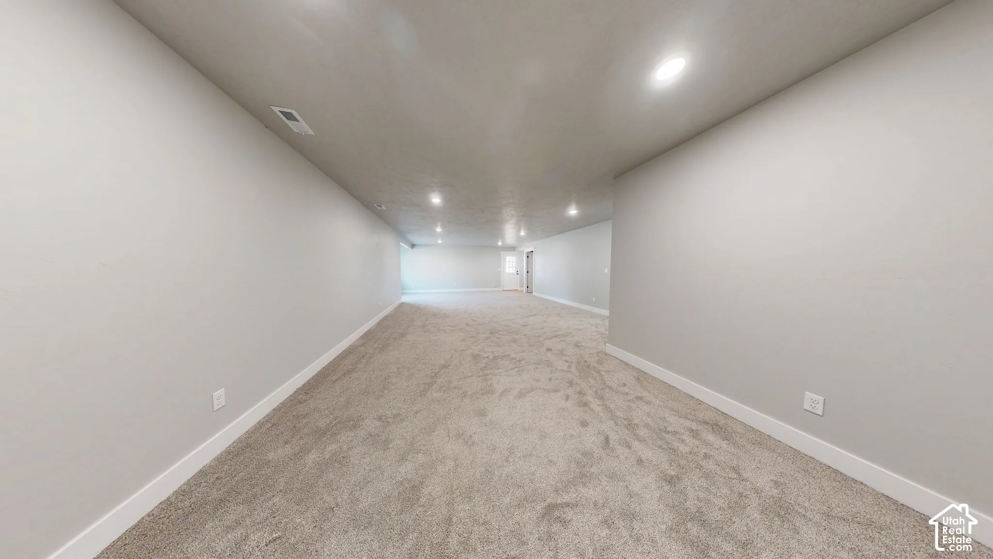 Expansive room featuring neutral-toned carpeting, recessed lighting, and light-colored wall finishes