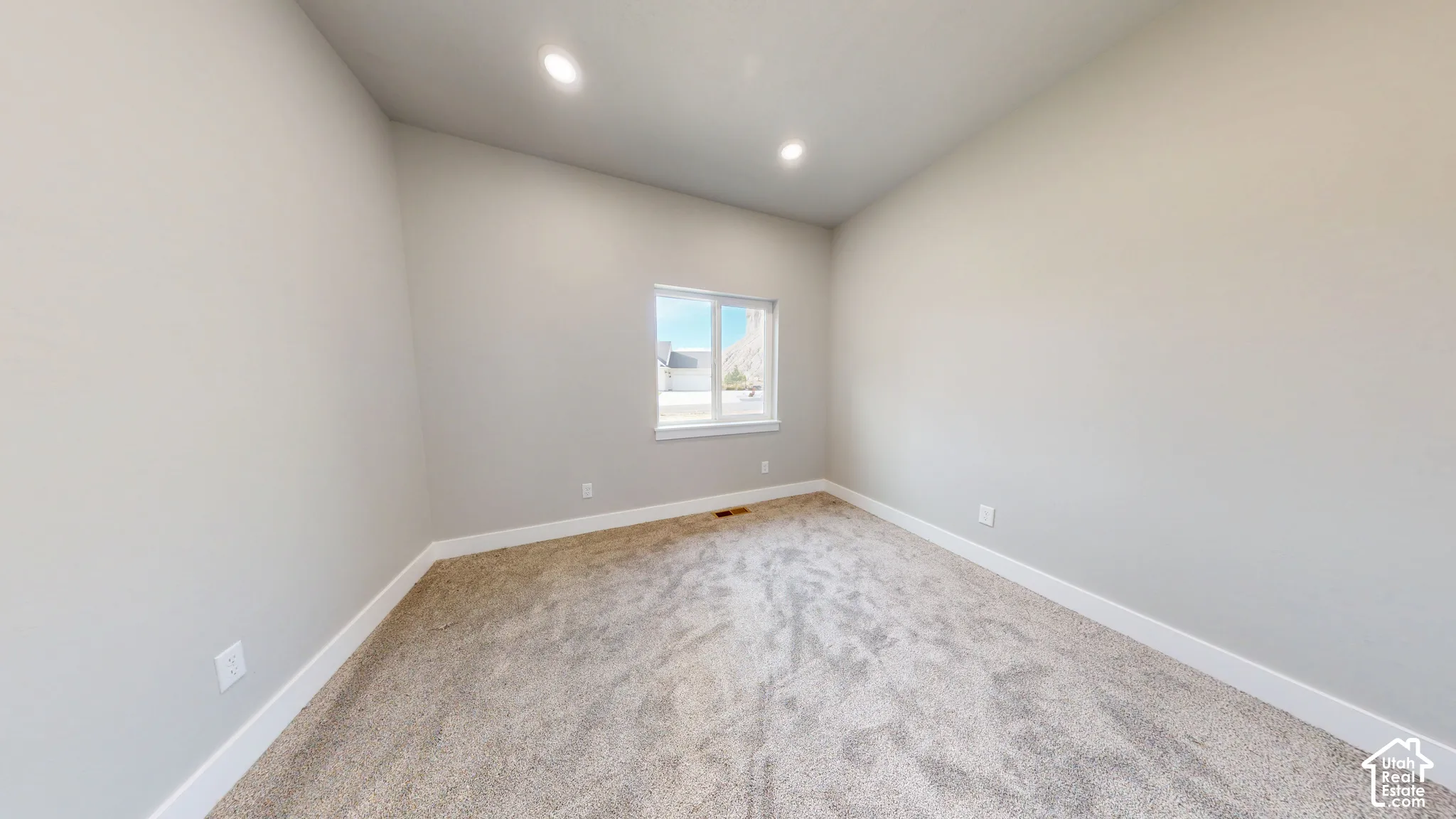 Neutral-toned room featuring high vaulted ceilings, recessed lighting, wall-to-wall carpeting, and a single-pane window