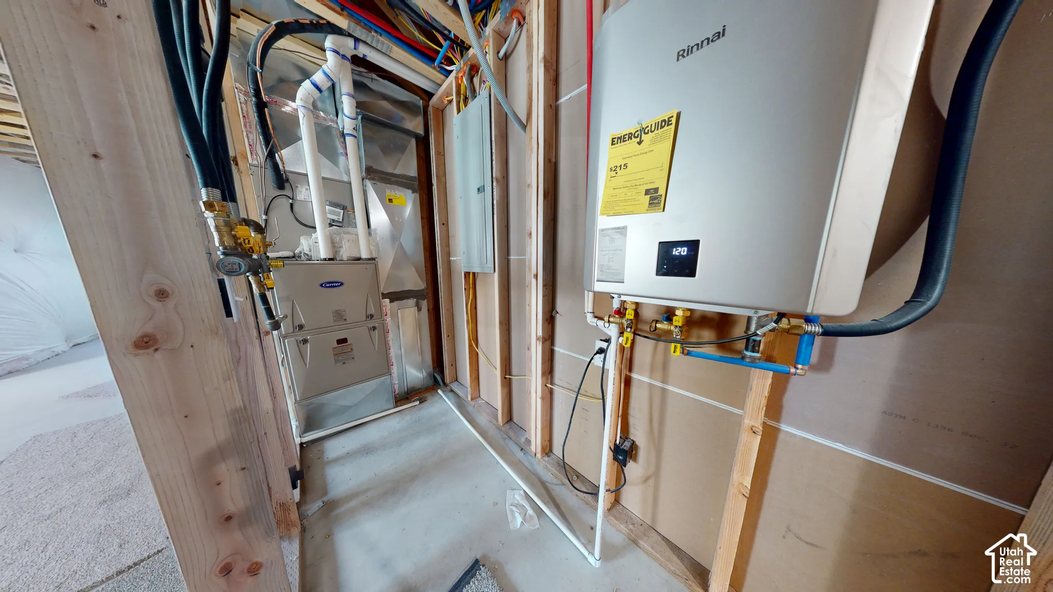 Utility space featuring a wall-mounted Rinnai tankless water heater, high-efficiency gas furnace, and electrical panel