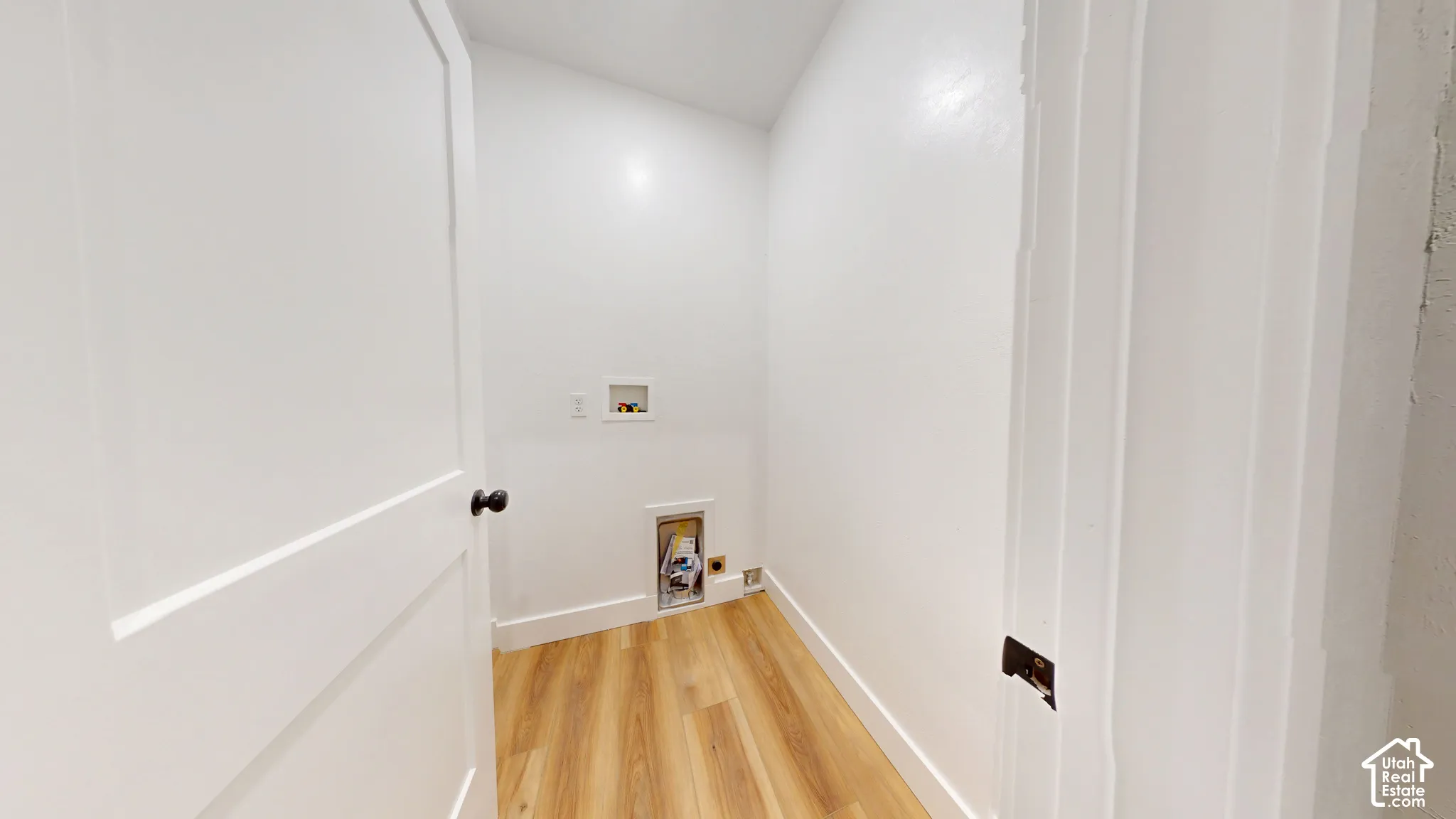 Utility closet featuring wood-finish flooring, white walls, and dedicated washer and dryer hookups