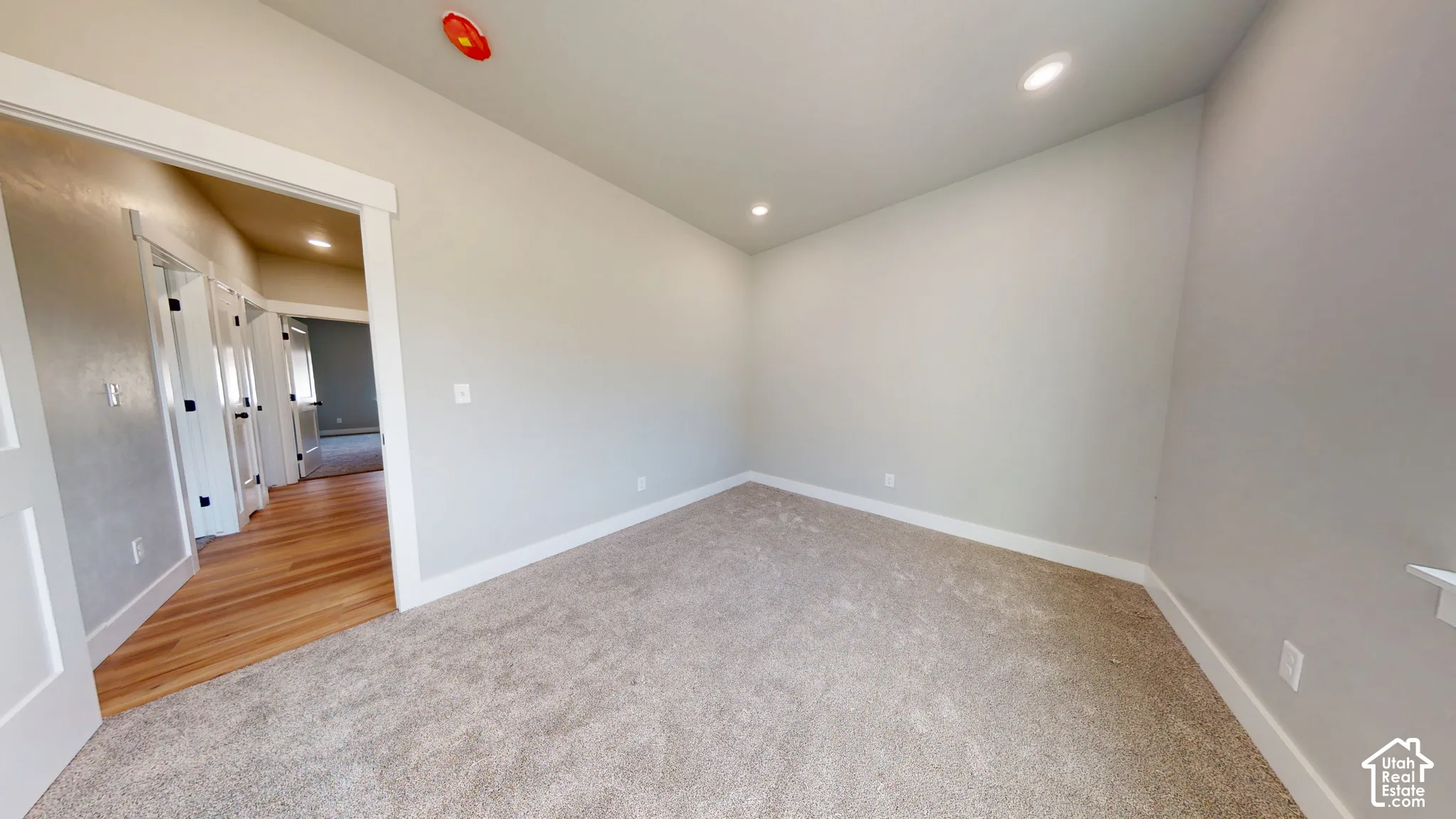 Neutral-toned room featuring wall-to-wall carpeting, recessed ceiling lighting, and wood-finish flooring in the exterior hall