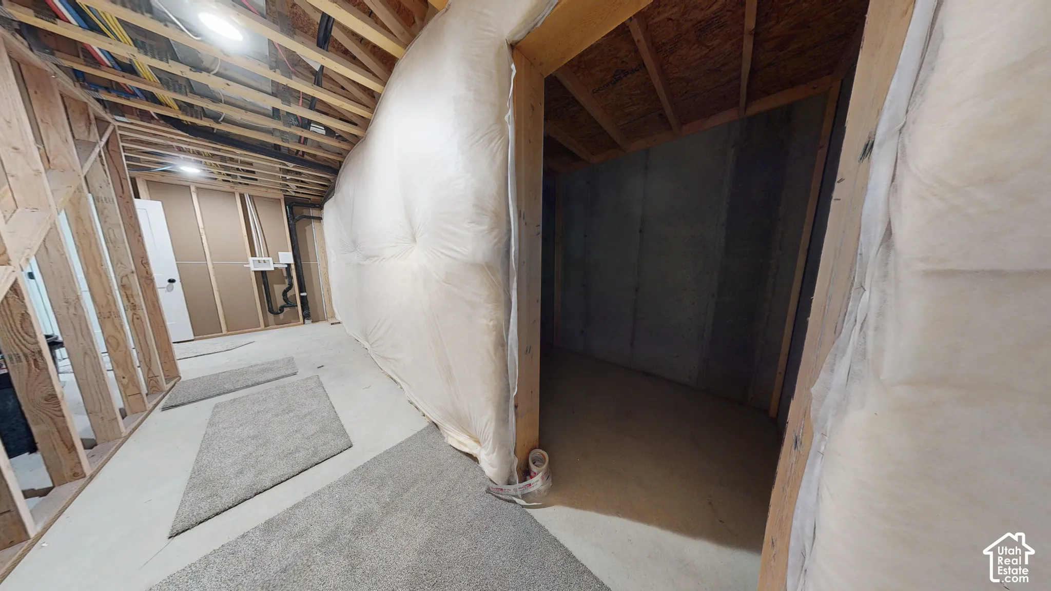 Unfinished space featuring exposed timber framing, concrete foundation walls, fiber insulation, and exposed ceiling joists